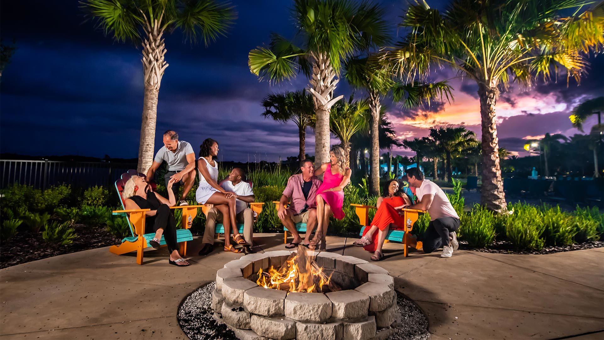 Couples gathered around a fire pit at night by the Salty Rim Bar & Grill at Margaritaville Resort Orlando.