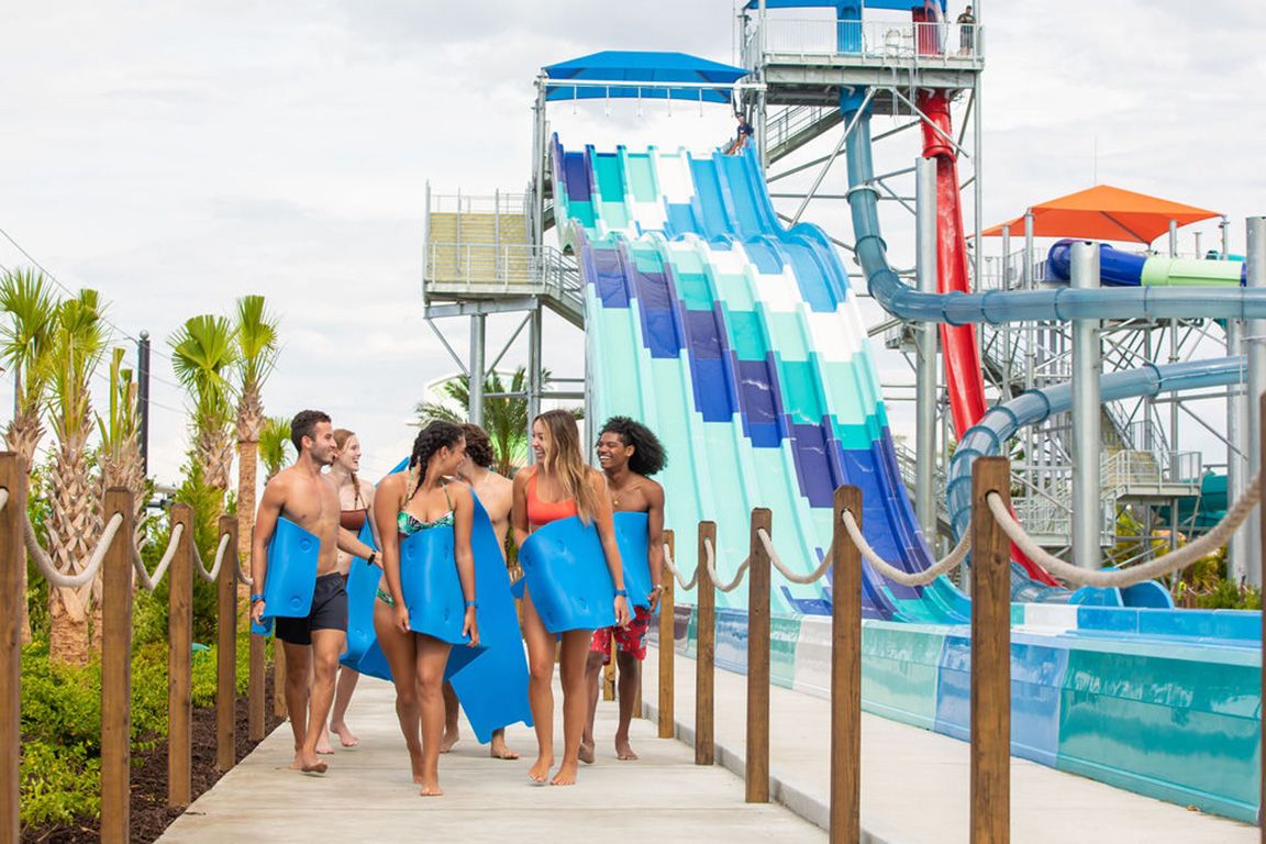 Friends with water slide mats walking together in Island H2O Water Park.