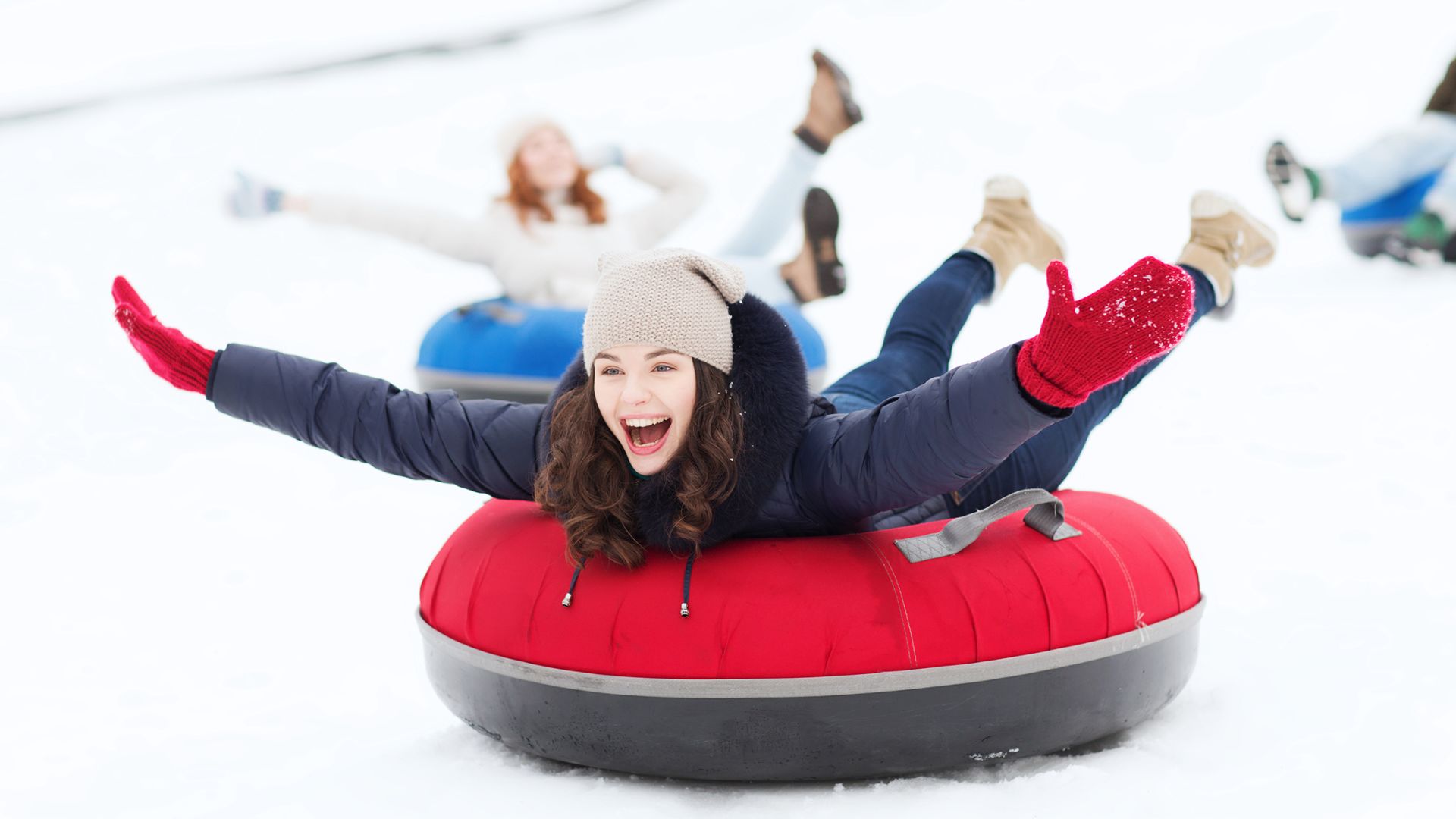 Girl snow tubing with her arms out