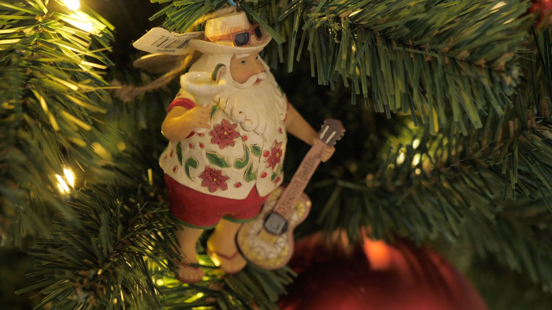 Christmas tree ornament of Santa Claus in a tropical outfit.