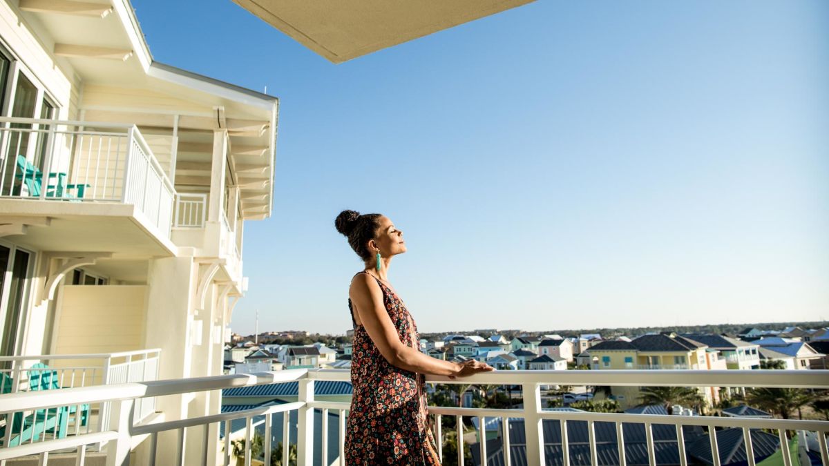 Woman standing on the balcony of a Margaritaville Resort Orlando suite on a sunny day.