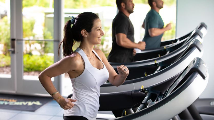 Woman running on a treadmill inside the Fins Up Fitness Center.