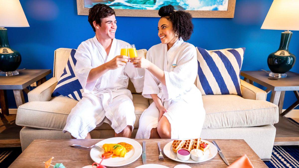 Couple in bath robes having brunch with orange juice in a Margaritaville Resort Orlando cottage.