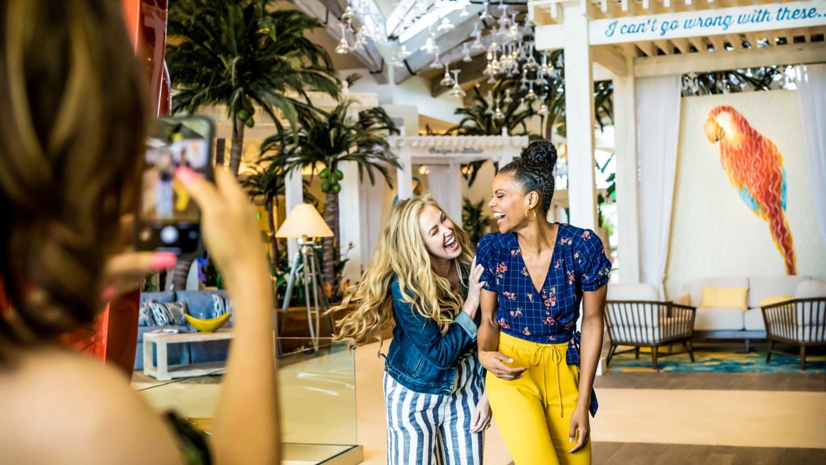 Two women laughing together as they walk through the Margaritaville Resort Orlando lobby.