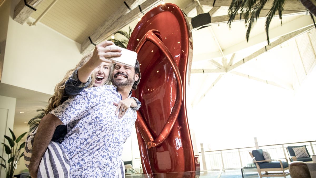 Couple taking a photo in front of the Margaritaville Resort Orlando flip flop