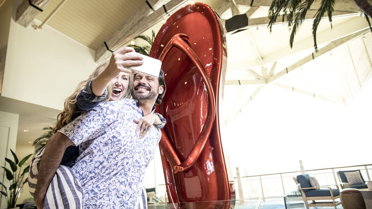 Couple taking a photo in front of the Margaritaville Resort Orlando flip flop