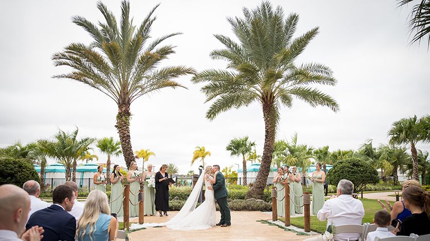 Bride and groom first kiss in front of palm tress