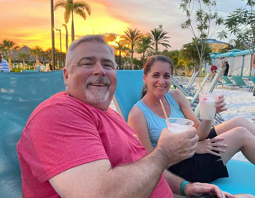 A couple sitting on lounge chairs holding cocktails
