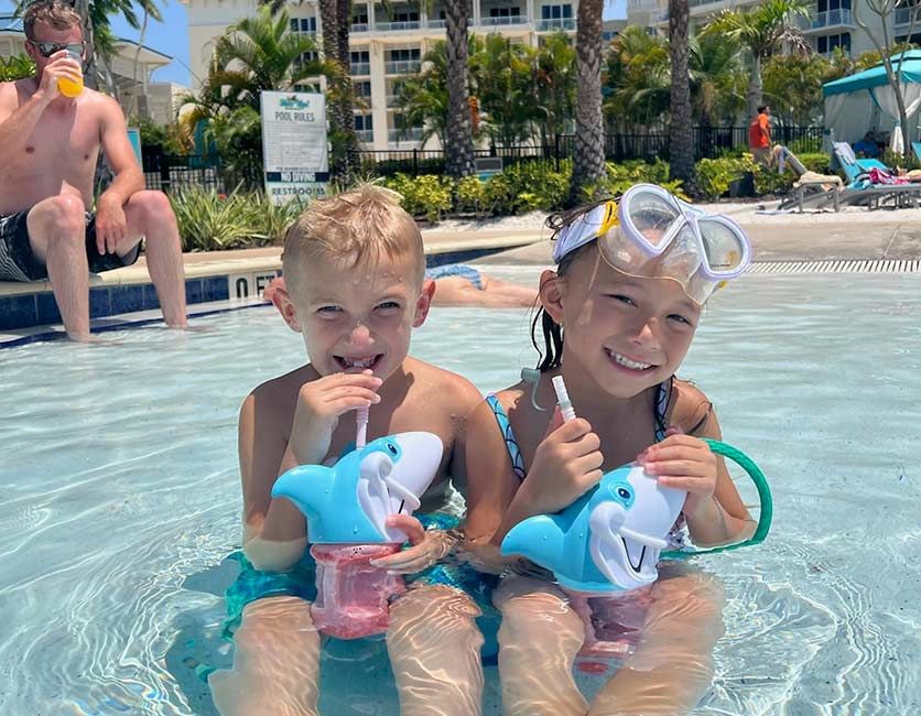 Kids sipping drinks in shark cups while sitting in the pool