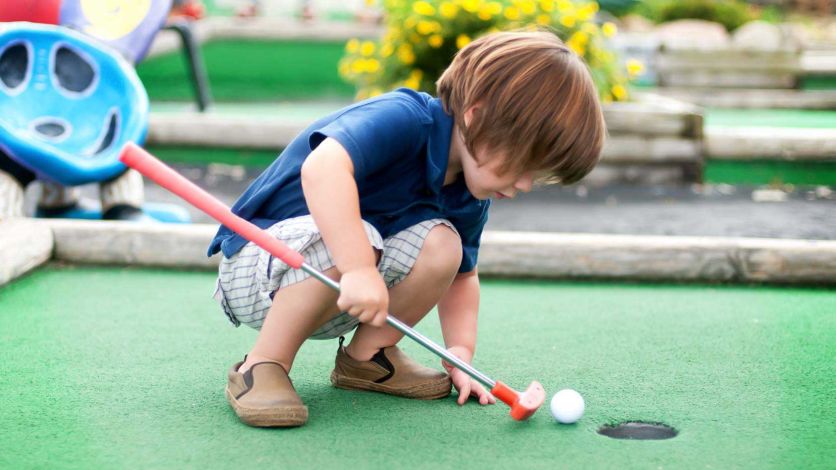 Young boy playing a round of mini golf