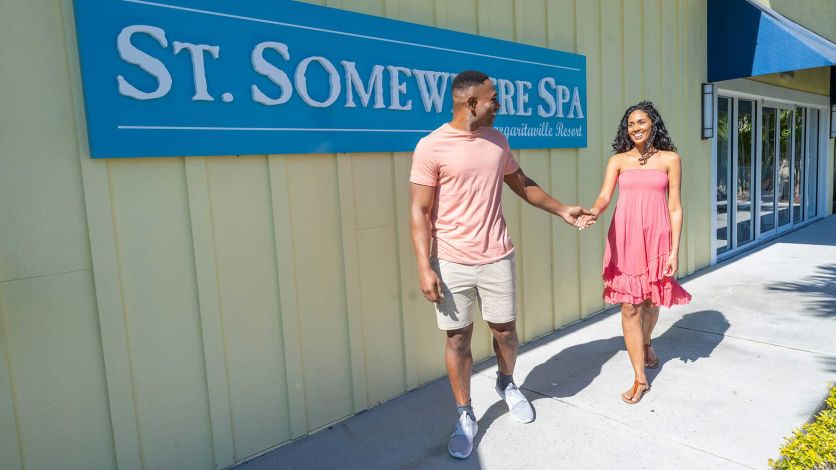 Couple holding hands in front of the St. Somewhere Spa sign at Margaritaville Resort Orlando
