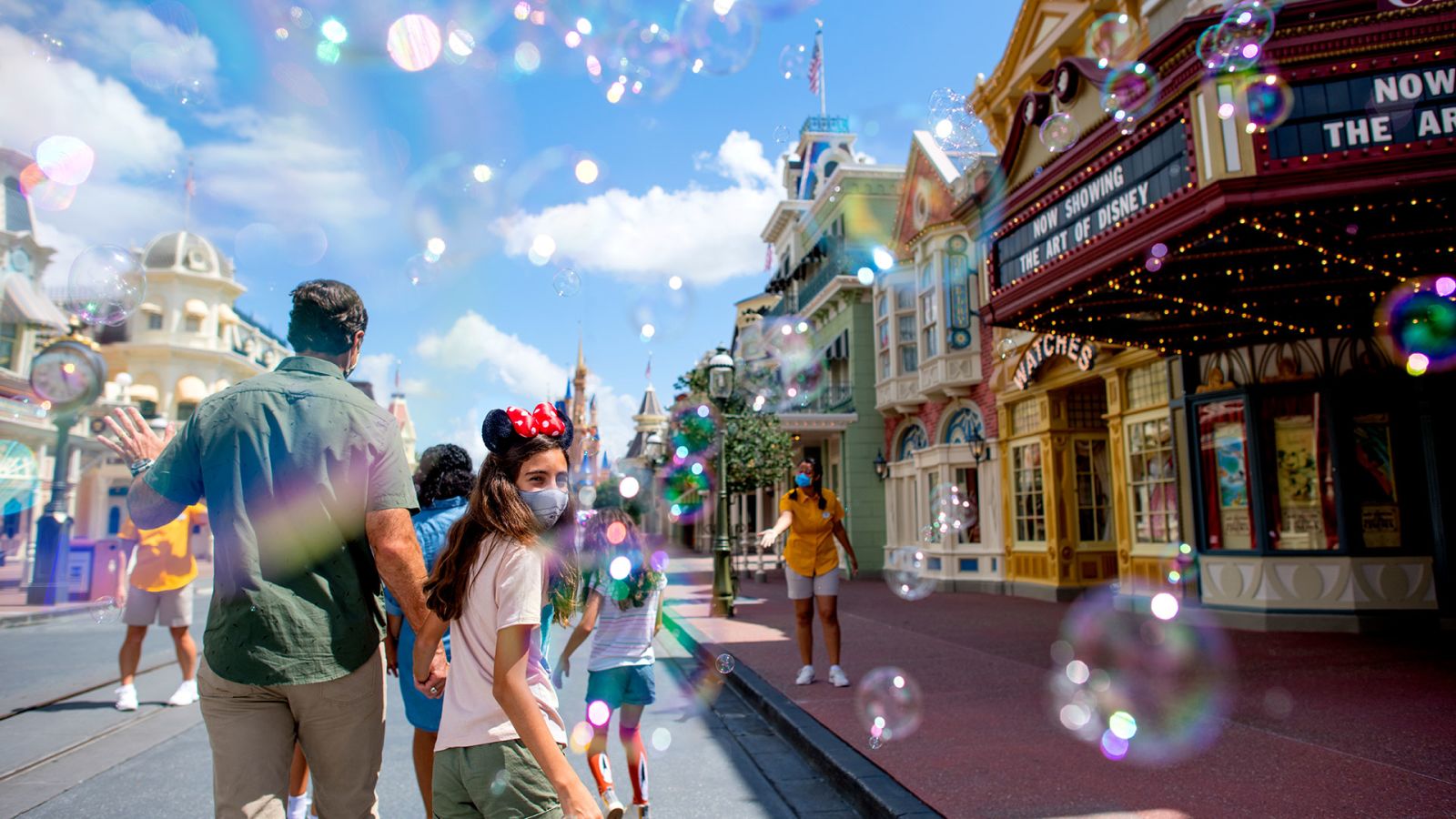Happy family wearing face masks walking into Walt Disney World's Magic Kingdom.