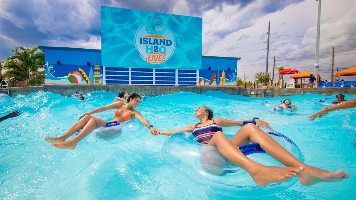 Couple holding hands on floating tubes in Island H2O Water Park's wave pool.