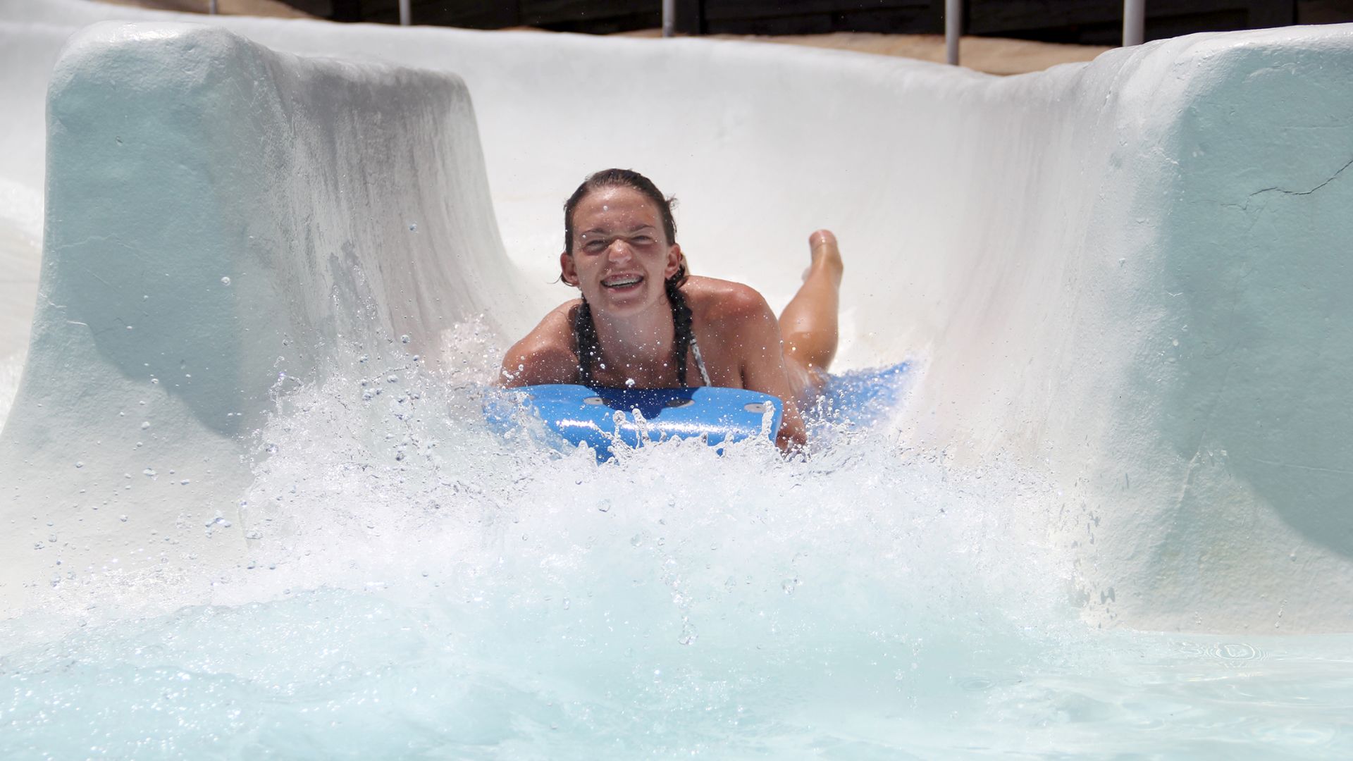 A Young Girl Riding A Wave On A Surfboard In The Water