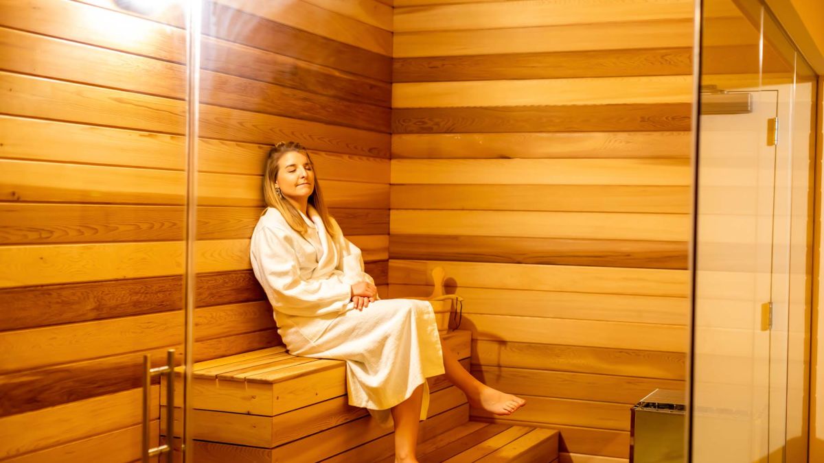 Woman Sitting Relaxed Inside A Sauna Room In St. Somewhere Spa.