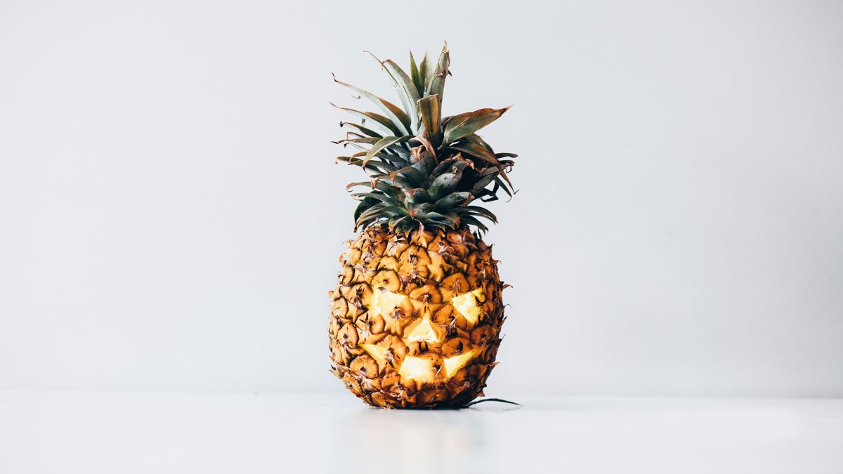 Pineapple carved like a jack-o'-lantern.