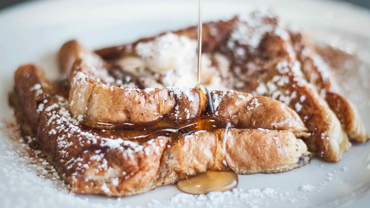 Stack of French toast with powdered sugar and syrup.