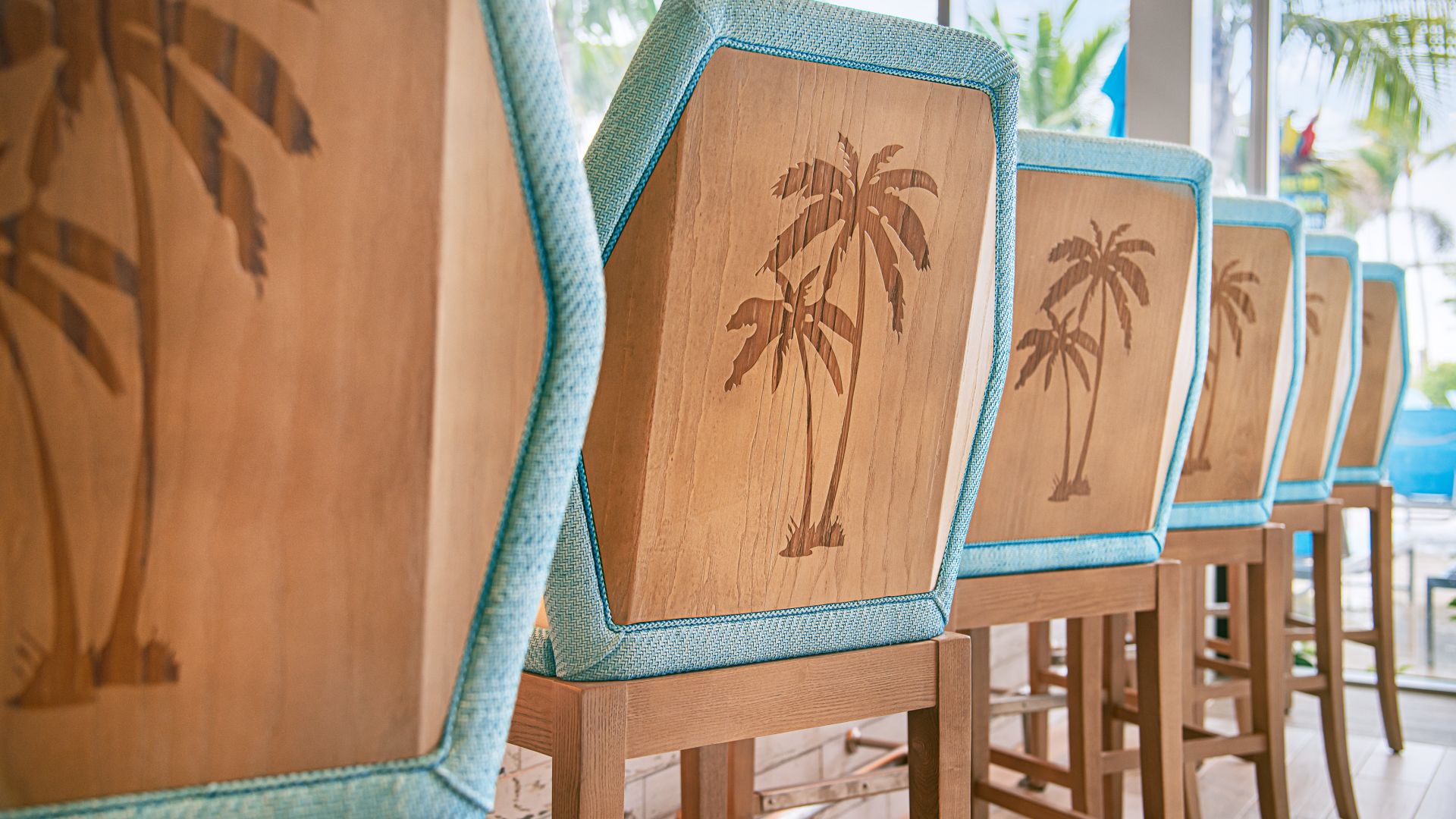 a photo of the backs of several bar stools showing two palm trees burned into the back of each of the chairs