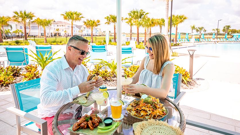 Couple eating food at a table by the pool