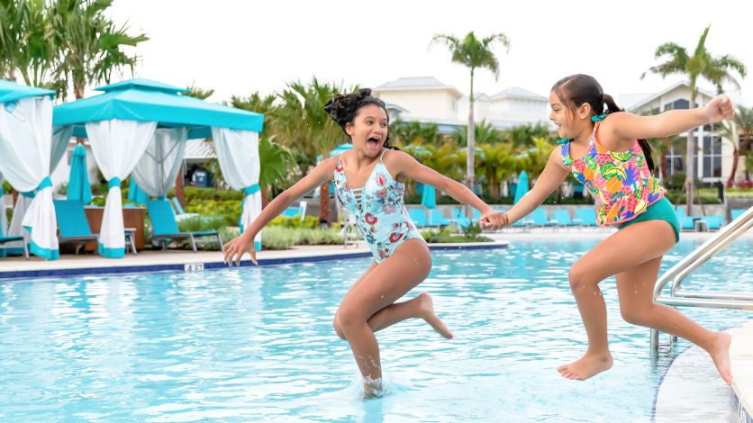 Kids holding hands as they jump into the resort pool.