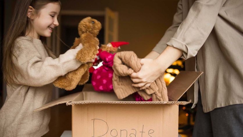 Young girl putting toys into a donation box
