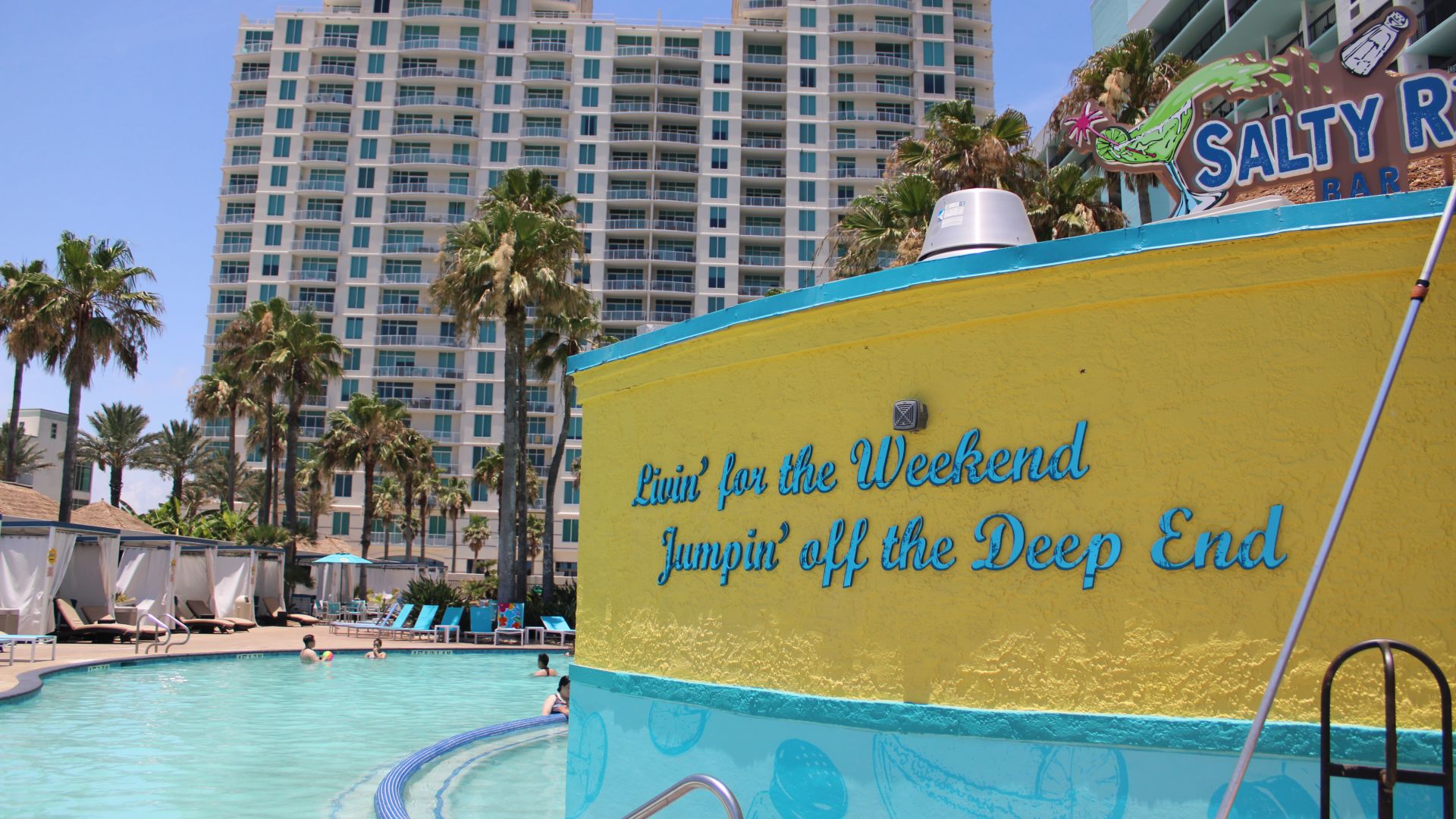 A Large Yellow Sign Next To A Pool With People In It