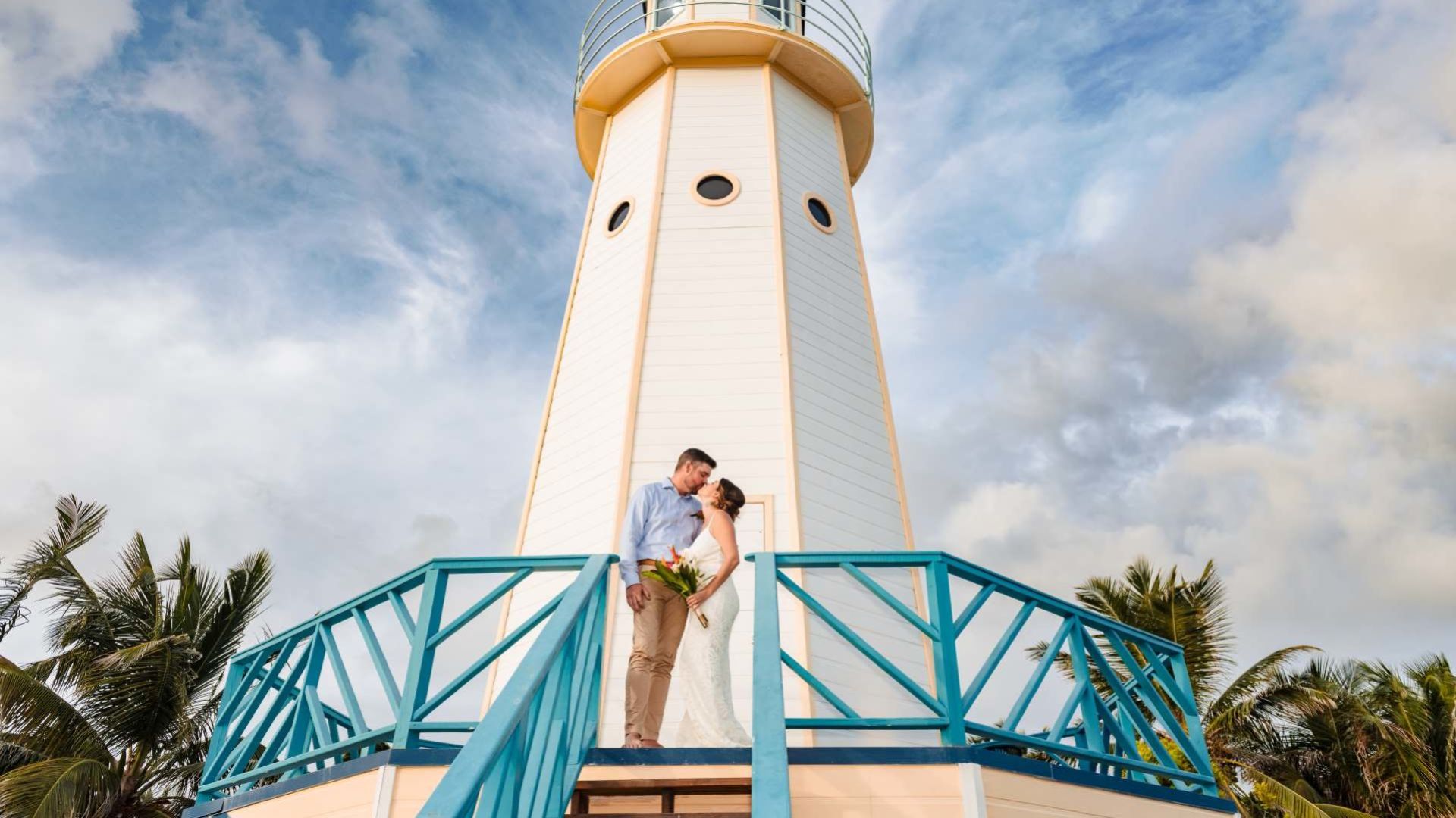 A Man And Woman Kissing On A Balcony With A Lighthouse In The Background