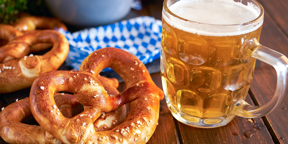 A Glass Of Beer Next To A Plate Of Donuts