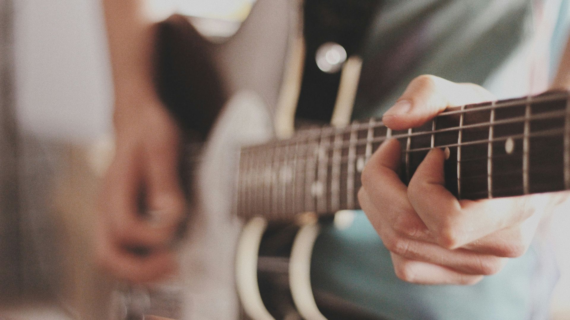 A Close-up Of Hands Playing A Guitar