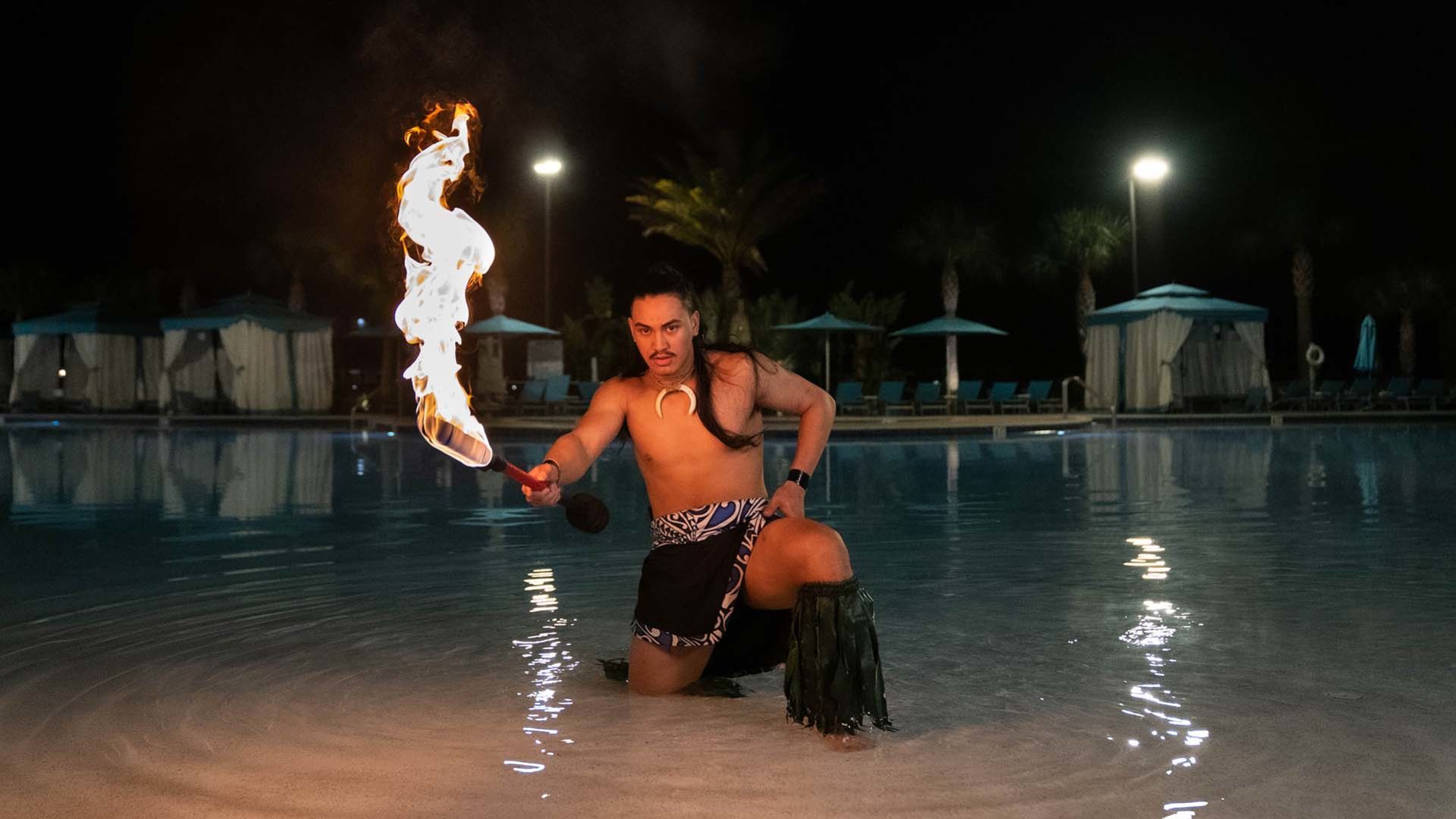 Fire dancer performing at the edge of Fins Right Pool’s zero entry at Margaritaville Resort Orlando