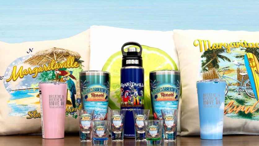 Various Margaritaville branded drinkware and pillows on a table